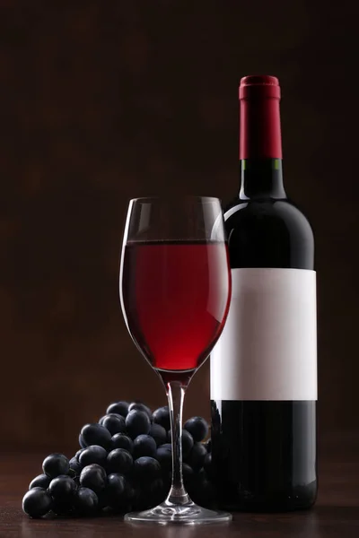 Botella de vino tinto con etiqueta con copa y uvas maduras — Foto de Stock