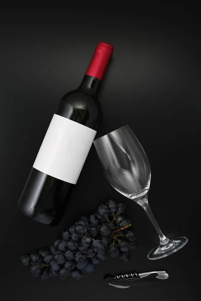 Garrafa de vinho tinto com rótulo com vidro e uvas maduras em blac — Fotografia de Stock