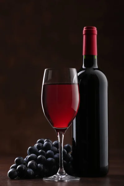 Botella de vino tinto con etiqueta con copa y uvas maduras — Foto de Stock