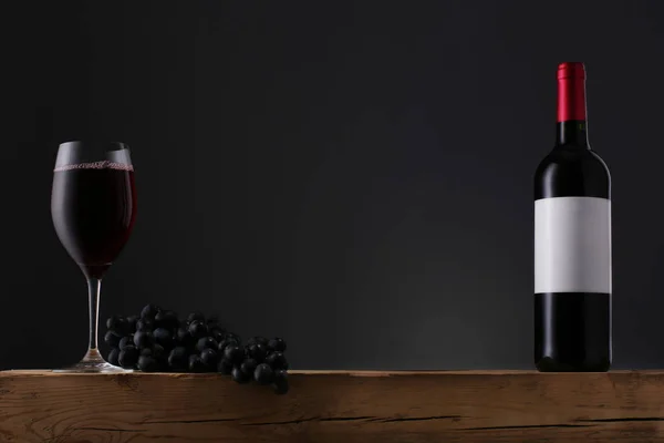 Garrafa de vinho tinto com rótulo e vinho na velha mesa de madeira — Fotografia de Stock