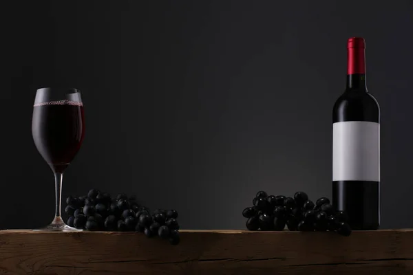 Garrafa de vinho tinto com rótulo e vinho na velha mesa de madeira — Fotografia de Stock