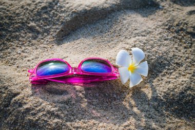 Güneş gözlüğü ve sahil kumu frangipani çiçek