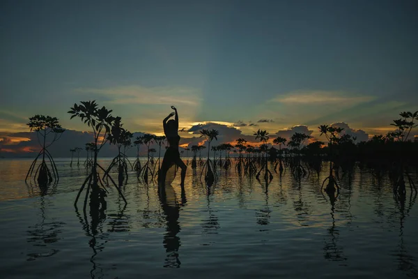 Bir uzun gün batımı renkli arka plan üzerinde sahilde dans içinde mutlu genç kadın