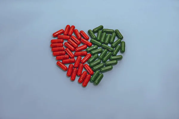 Heart of pills and capsules isolated on blue background