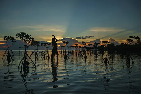 Bir uzun gün batımı renkli arka plan üzerinde sahilde dans içinde mutlu genç kadın