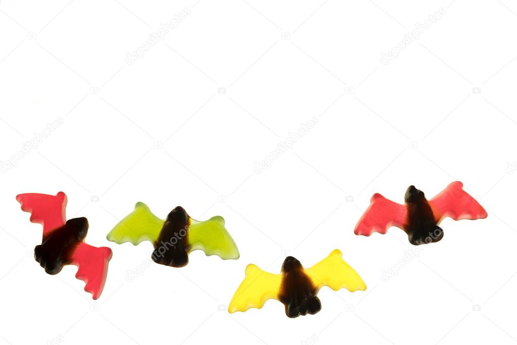 multicolored gummy jelly bat candies over white background