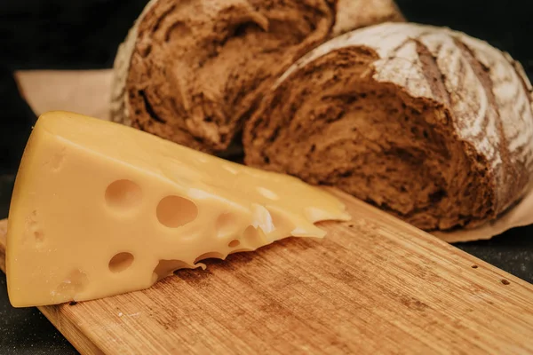 Tahta siyah arka plan üzerinde kağıt üzerinde taze ekmek ve peynir