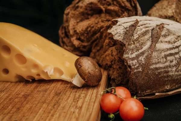 Champignons mantar, siyah arka plan üzerinde kiraz domates ekmek ve peynir