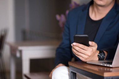 Asya iş adamı seçici odak kafede onun smartphone ile çalışma.
