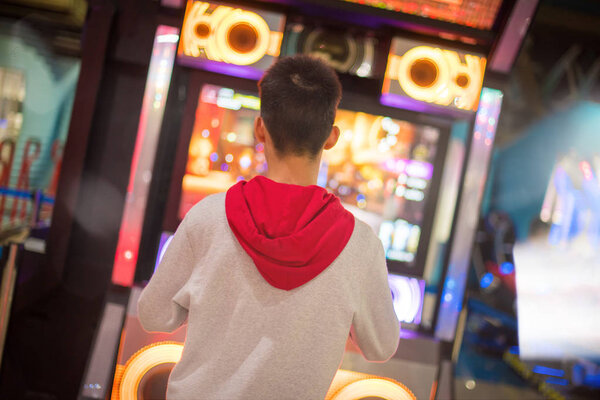 A boy dancing with game arcade machine in selective focus.