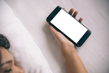 Asyalı kadının el sabah yatak boş ekran smartphone kullanarak.