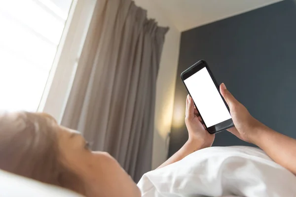 Asyalı kadının el sabah yatak boş ekran smartphone kullanarak.