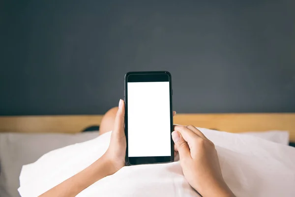 Asyalı kadının el sabah yatak boş ekran smartphone kullanarak.