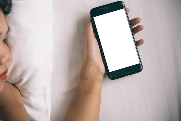 Asyalı kadının el sabah yatak boş ekran smartphone kullanarak.