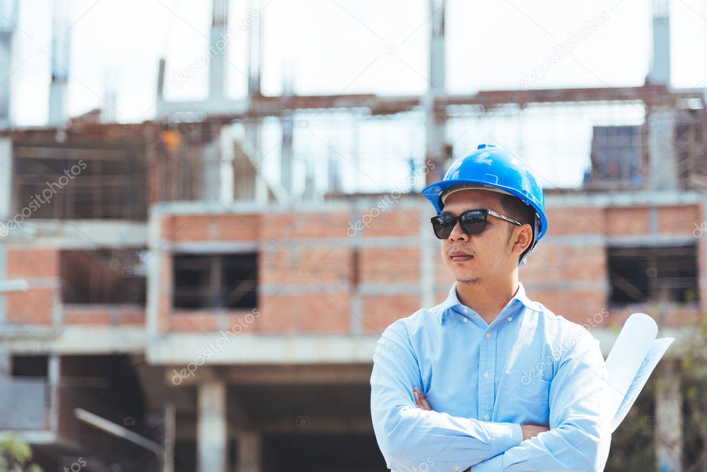 Civil engineer with blue safety helmet and sunglasses at construction site.