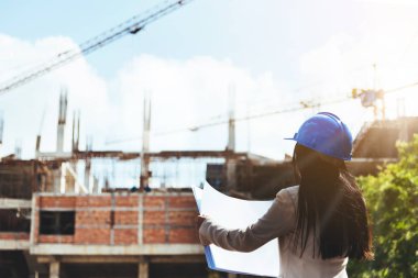 Asyalı kadın mimar inşaat sitede çalışma ilerleme kontrol mavi Güvenlik kask giyiyor.