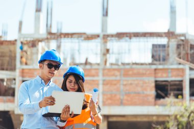Asya adam inşaat mühendisi laptop ve Asyalı kadın mimar inşaat alanında tokalaşırken çizim blueprint holding holding kadar kapatın.