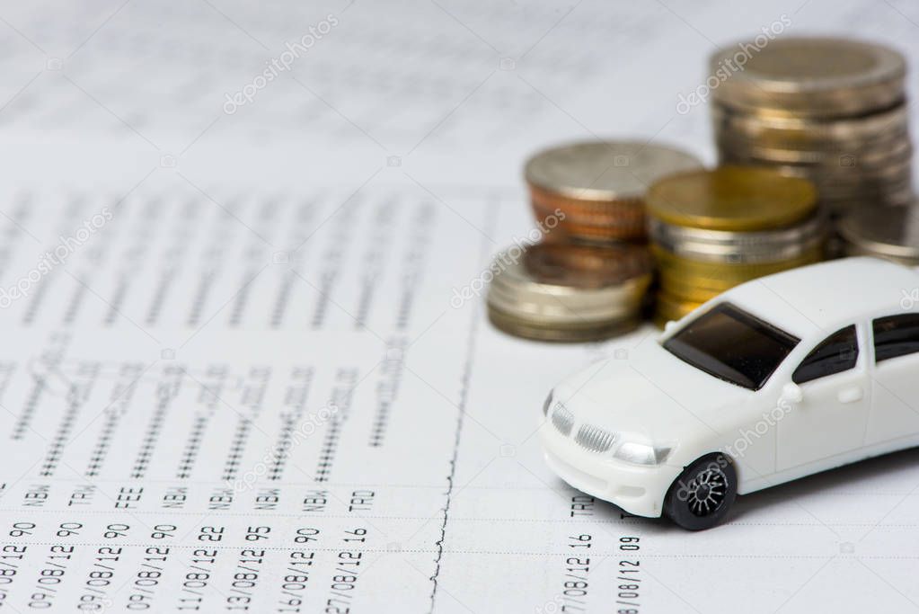 White car and coins on the account book in selective focus, Concept: Buy, new car, finance, investment.