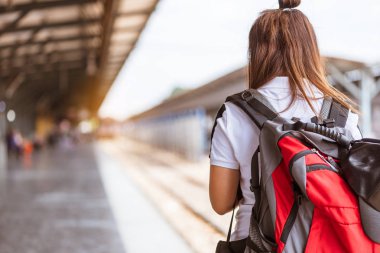 Trai tren bekleyen genç Asyalı kadın turist geri görünümü