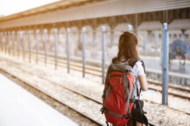 Trai tren bekleyen genç Asyalı kadın turist geri görünümü