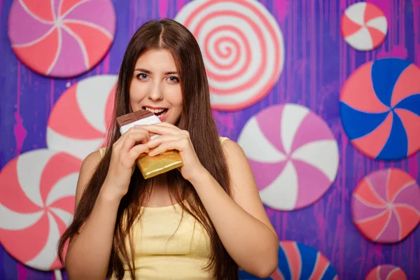 Bella Donna Morde Una Tavoletta Cioccolato Uno Sfondo Astratto Muro — Foto Stock