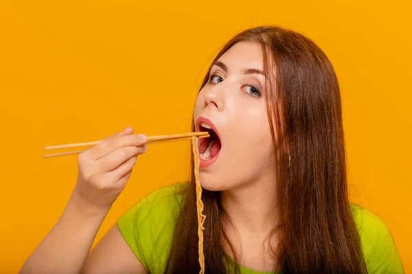 Γυναίκα Τρώει Στιγμιαία Νουντλς Κινέζικα Ξυλάκια Φωτογραφία Στούντιο Κίτρινο Φόντο — Φωτογραφία Αρχείου