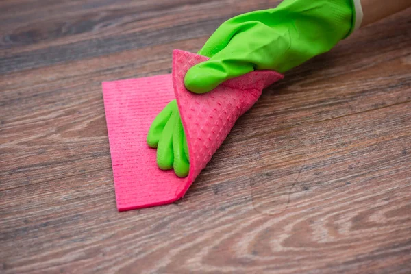 stock image Closeup of a hand in a green rubber glove rubbing a wet wooden surface. The concept of disinfection of premises, the prevention of viral and bacterial diseases. Cleaning wooden surfaces.