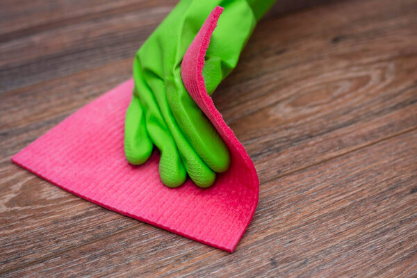 Крупный план руки в зеленой резиновой перчатке, потирая влажную деревянную поверхность. Концепция дезинфекции предпосылок, профилактики вирусных и бактериальных заболеваний. Очистка деревянных поверхностей
.