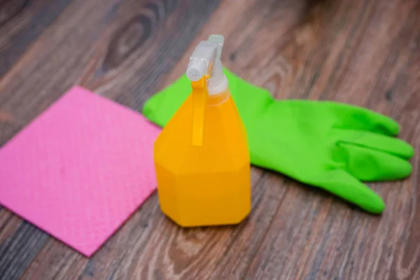 Close-up of a spray bottle, rubber gloves and a wet rag lying on the floor. The concept of disinfection of premises, the prevention of viral and bacterial diseases. Cleaning wooden surfaces.