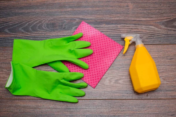 Close-up of a spray bottle, rubber gloves and a wet rag lying on the floor. The concept of disinfection of premises, the prevention of viral and bacterial diseases. Cleaning wooden surfaces.