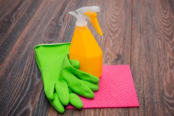 Close-up of a spray bottle, rubber gloves and a wet rag lying on the floor. The concept of disinfection of premises, the prevention of viral and bacterial diseases. Cleaning wooden surfaces.