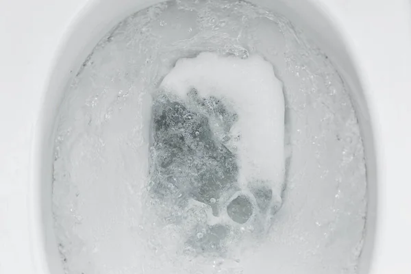 Top view, flushing water in the toilet close-up.