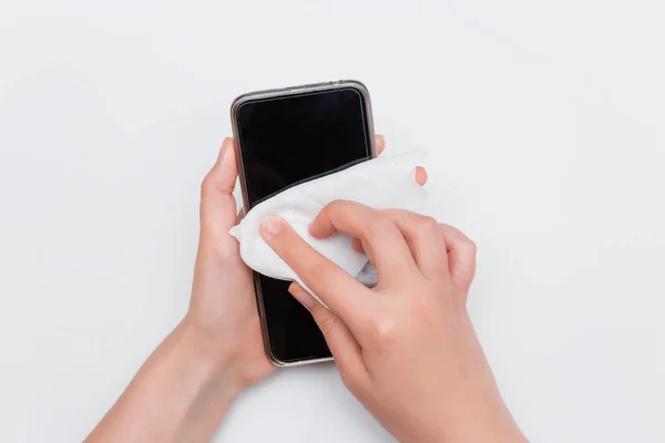 First-person view, hands wipe the smartphone with a wet wipe, isolated on a white background. The concept of the need for regular disinfection of gadgets.