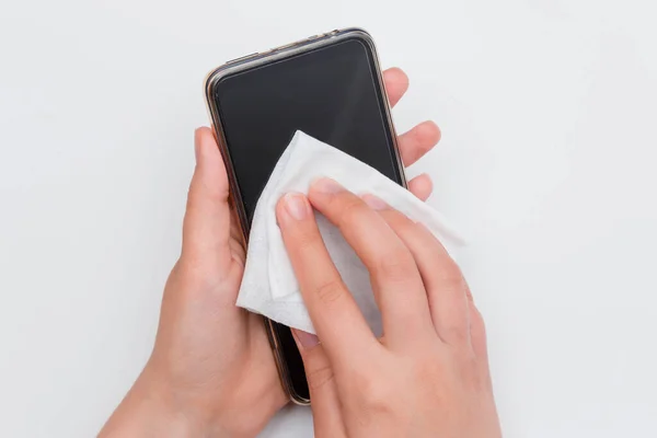 First-person view, hands wipe the smartphone with a wet wipe, isolated on a white background. The concept of the need for regular disinfection of gadgets.