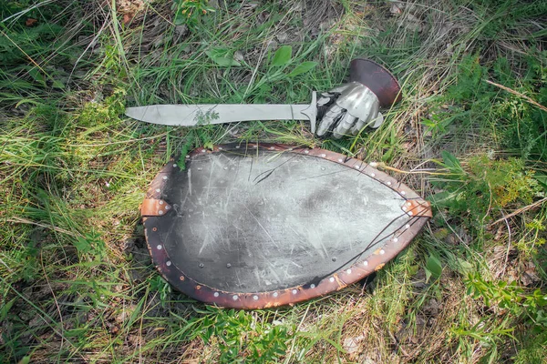 一个蒙古战士的剑 一个钢手套和一个盾牌躺在地上的青草 在战斗后被带走了游牧 草原士兵的中世纪武器 — 图库照片