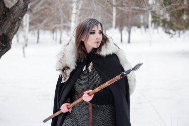 Kadın, ormanda kışın ortaçağ Viking Çağı 'nın savaşçısıdır. Zincirli zırh, pelerin, kürk, deri pantolon ve ellerinde mızrakla botlar. Yüzünde savaş boyası.