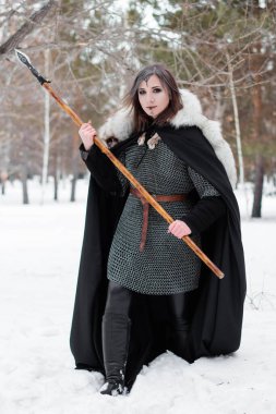 Kadın, ormanda kışın ortaçağ Viking Çağı 'nın savaşçısıdır. Zincirli zırh, pelerin, kürk, deri pantolon ve ellerinde mızrakla botlar. Yüzünde savaş boyası.