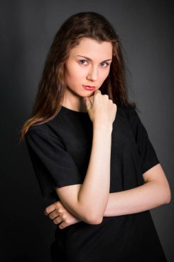Siyah elbiseli, uzun saçlı güzel bir genç kadının portresi. Stüdyo fotoğrafı, gri arka planda. Temiz ciltli bir model..