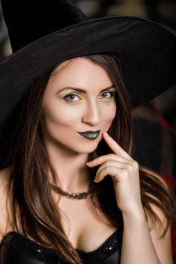 Siyah şapkalı yeşil makyajlı güzel, genç bir cadının portresi. Stüdyo fotoğrafı, temiz ciltli bir model, Cadılar Bayramı..