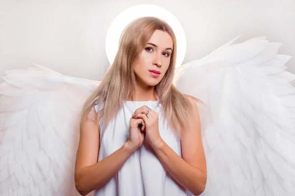 背中の後ろに大きな白い翼と彼の頭の上にハローを持つ白いドレスの天使 幻想的な外観の魅力的な女の子の肖像画 — ストック写真