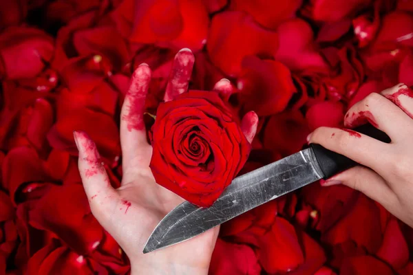 在血泊中紧握双手 手持刀和玫瑰芽 与玫瑰和花瓣相映成趣 — 图库照片