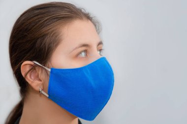 Beyaz bir arka planda izole edilmiş, yeniden kullanılabilir maske takmış bir kızın portresi. Eczanelerde tek kullanımlık tıbbi maske sıkıntısı ve yeniden kullanılabilir maskelerin popülerliği..