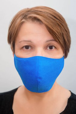 Beyaz arka planda yeniden kullanılabilir maske takan orta yaşlı bir kadının portresi. Eczanelerde tek kullanımlık tıbbi maske sıkıntısı ve yeniden kullanılabilir maskelerin popülerliği..