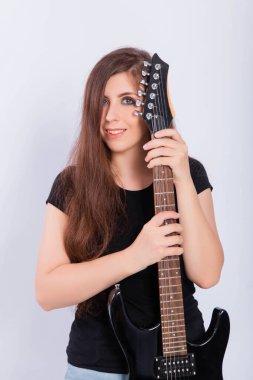 Siyah tişörtlü genç bir kadının portresi. Elinde beyaz arka planda izole edilmiş elektro gitar boynu var..