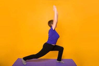 Yoga yapan bir kadın sarı arka planda duruyor..