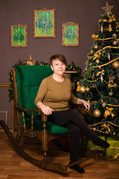 暖炉とクリスマスツリーを背景に 年老いた女性がロッキングチェアに座っています — ストック写真