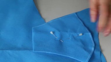 Bir terzinin elleri, mavi bir bezin desenine göre kesilmiş. Maske kesme makası. Bir salgın sırasında tıbbi maske eksikliği kavramı, bireysel maske terziliği.