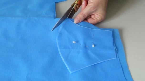 裁缝师的手 根据蓝色布上的图案裁剪 剪断口罩 大流行病期间医疗面罩短缺的概念 个别定制面罩 — 图库视频影像