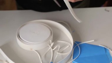 Tıbbi maske takmak için elastik bant kesen kadınların ellerini kapatın. Koronavirüs salgını sırasında maske dikmek. Koruyucu maske eksikliği kavramı.