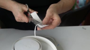 Tıbbi maske takmak için elastik bant kesen kadınların ellerini kapatın. Koronavirüs salgını sırasında maske dikmek. Koruyucu maske eksikliği kavramı.